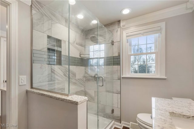 bathroom with a shower with door, vanity, and toilet