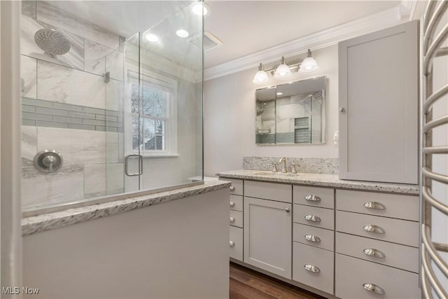 bathroom featuring hardwood / wood-style floors, vanity, a shower with door, and ornamental molding