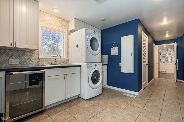 laundry room with light tile patterned floors, sink, beverage cooler, and stacked washer / dryer