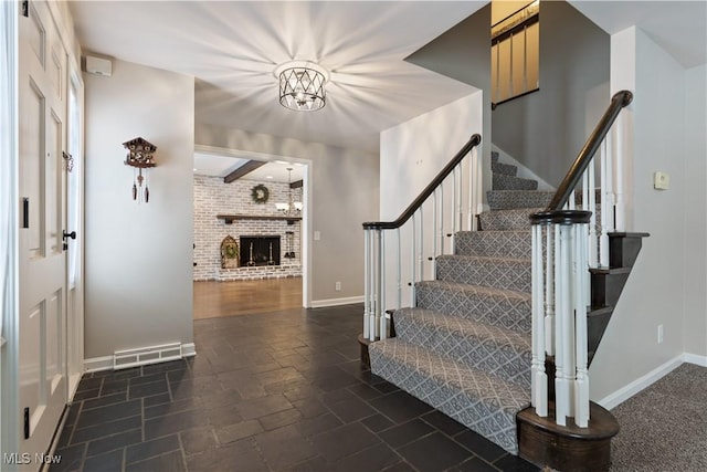 stairway with beamed ceiling and a brick fireplace