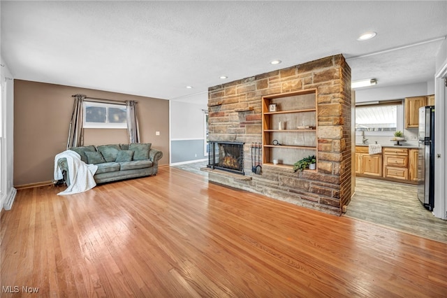 unfurnished living room with a textured ceiling, light hardwood / wood-style floors, and a fireplace