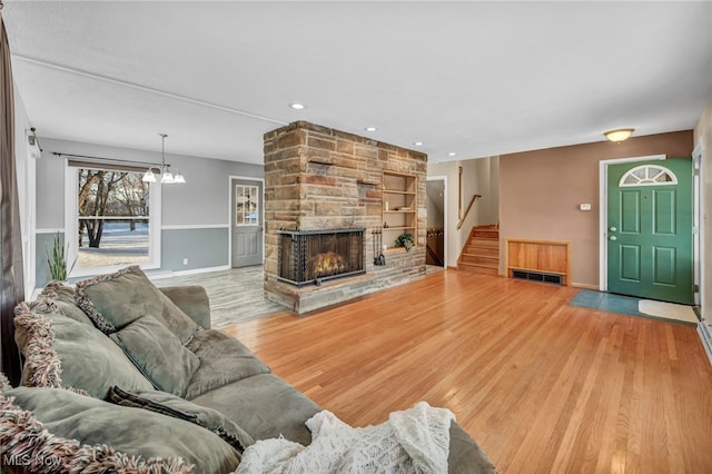 living room featuring a fireplace, hardwood / wood-style flooring, and a notable chandelier