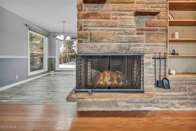 room details with a chandelier, wood-type flooring, and a stone fireplace