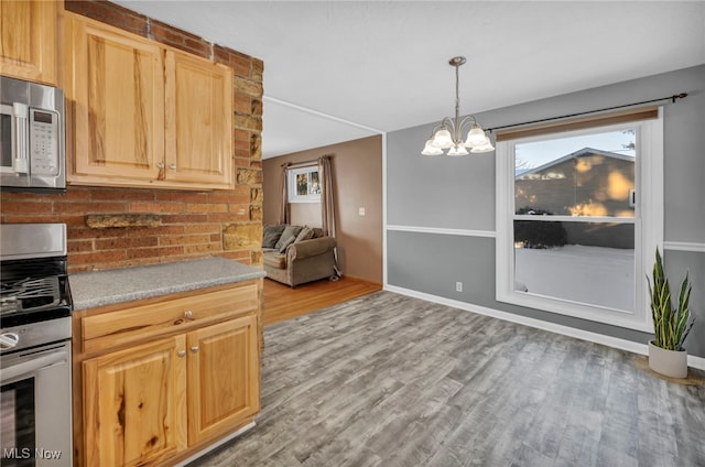 kitchen with light hardwood / wood-style flooring, a notable chandelier, pendant lighting, light brown cabinetry, and appliances with stainless steel finishes