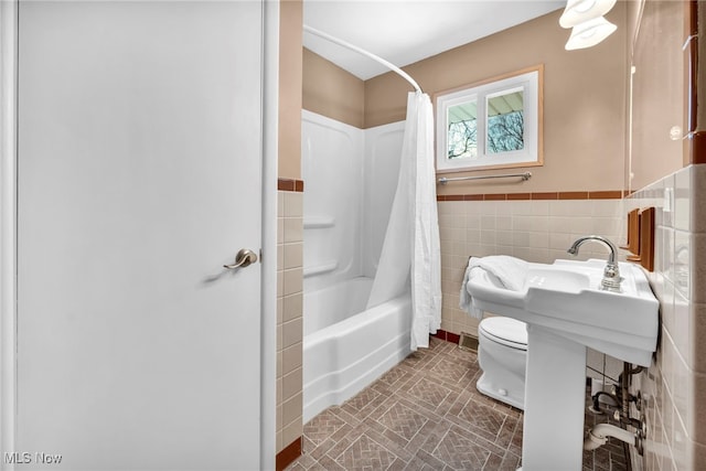 bathroom featuring toilet, tile walls, and shower / tub combo