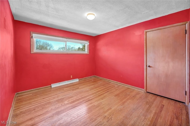 unfurnished room featuring a baseboard heating unit, a textured ceiling, and light hardwood / wood-style flooring