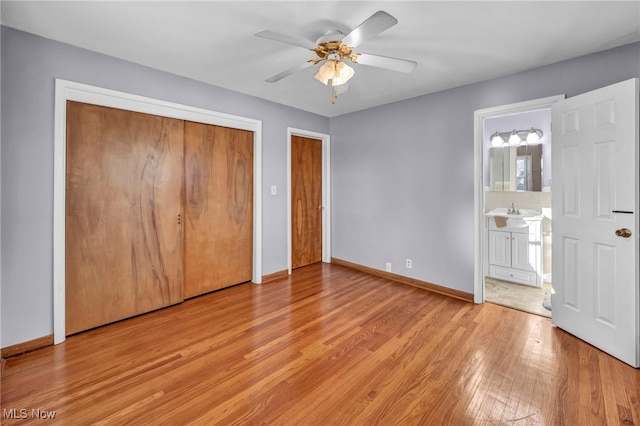 unfurnished bedroom featuring light wood-type flooring, ensuite bathroom, ceiling fan, and sink