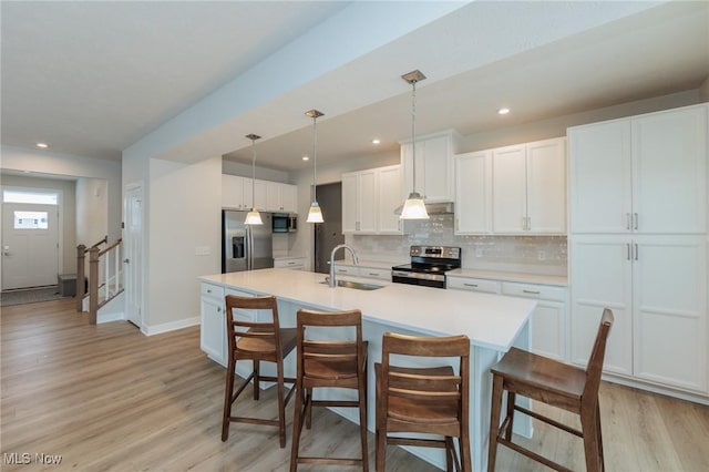 kitchen with white cabinetry, sink, a kitchen island with sink, decorative backsplash, and appliances with stainless steel finishes