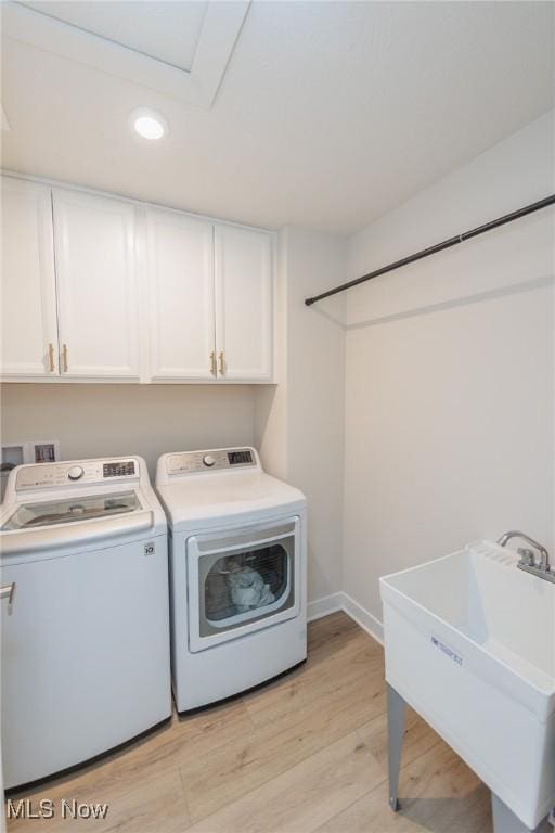 laundry room with cabinets, sink, washer and dryer, and light hardwood / wood-style floors