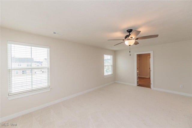 carpeted empty room with a wealth of natural light and ceiling fan