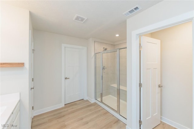 bathroom with hardwood / wood-style flooring, vanity, and a shower with door