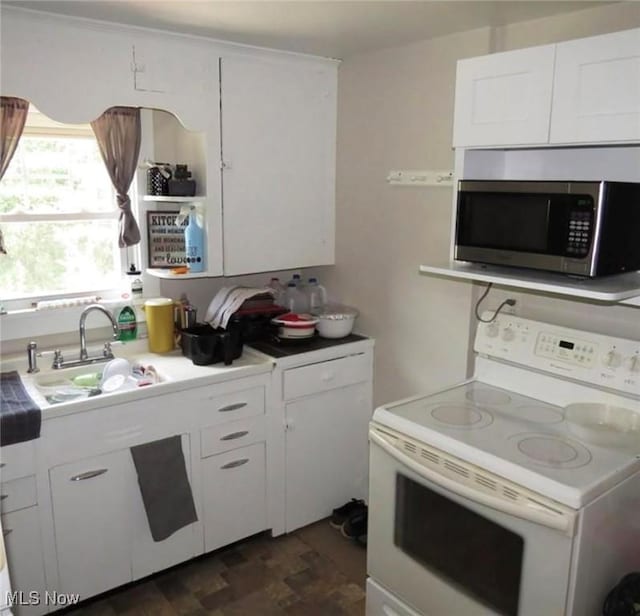 kitchen with white electric range oven, white cabinetry, and sink