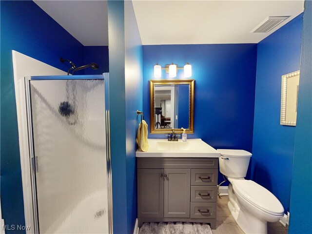 bathroom featuring vanity, toilet, and a shower with shower door