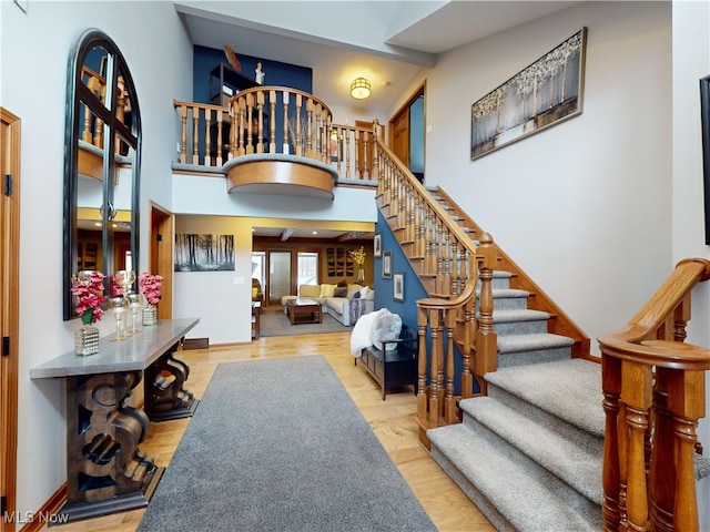 stairs with hardwood / wood-style floors and a high ceiling