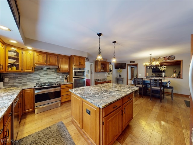 kitchen featuring stainless steel appliances, tasteful backsplash, a chandelier, pendant lighting, and a kitchen island