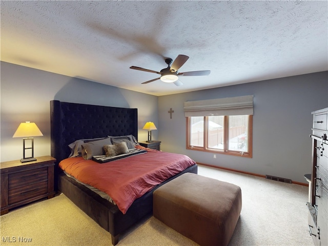 carpeted bedroom featuring ceiling fan and a textured ceiling