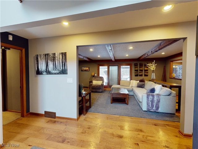 living room featuring beamed ceiling and light hardwood / wood-style floors