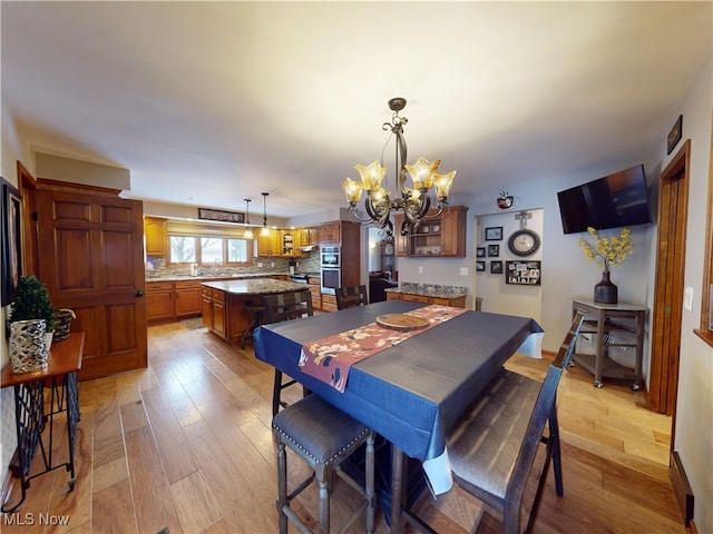 dining room with light hardwood / wood-style floors and a notable chandelier