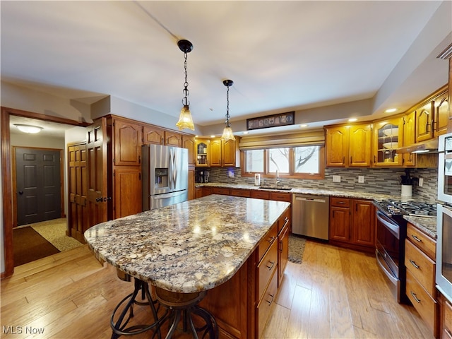 kitchen with a kitchen breakfast bar, a center island, stainless steel appliances, and tasteful backsplash