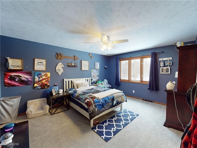 bedroom with ceiling fan, carpet floors, and a textured ceiling