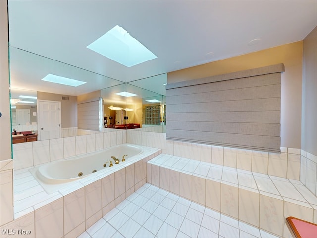 bathroom featuring a skylight and tiled tub