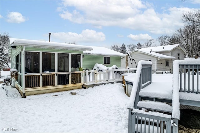 snow covered back of property featuring a deck