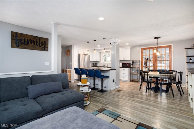 living room featuring french doors, light wood-type flooring, and plenty of natural light