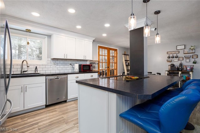 kitchen with black appliances, a kitchen island, white cabinets, and sink