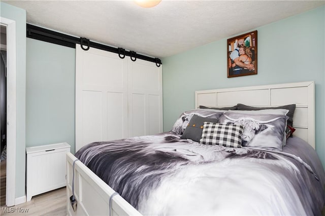 bedroom featuring a textured ceiling and light hardwood / wood-style flooring