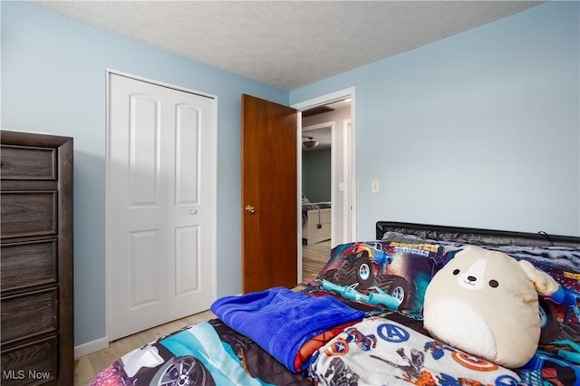 bedroom with a closet, a textured ceiling, and light hardwood / wood-style flooring