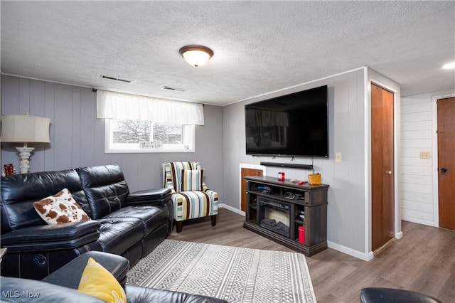 living room with a textured ceiling, hardwood / wood-style flooring, and wooden walls