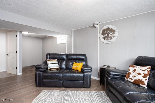 living room with wood walls, a textured ceiling, and hardwood / wood-style flooring