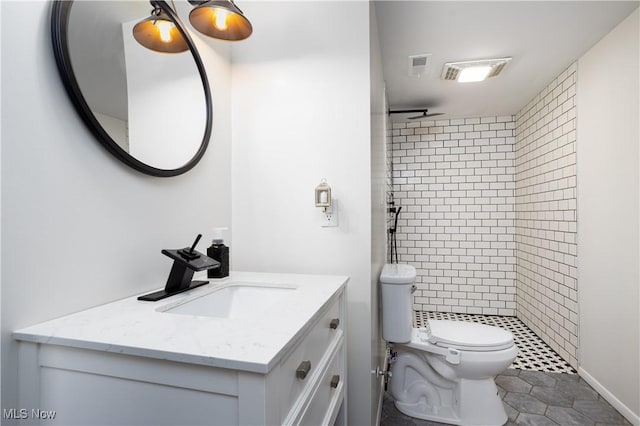 bathroom with tile patterned flooring, a tile shower, vanity, and toilet