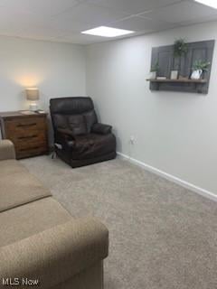 living room featuring carpet floors and a drop ceiling