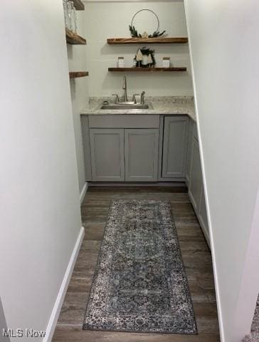 bar featuring gray cabinets, dark hardwood / wood-style floors, and sink