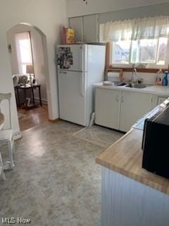 kitchen featuring a wealth of natural light, sink, and white refrigerator