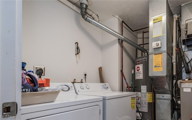 clothes washing area featuring a textured ceiling, gas water heater, and washing machine and clothes dryer