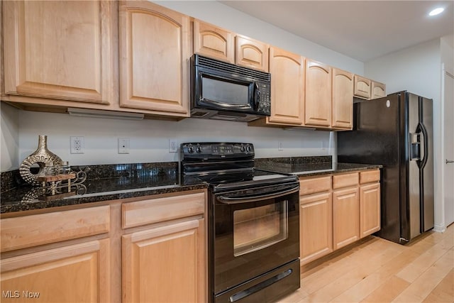 kitchen featuring black appliances, light hardwood / wood-style flooring, dark stone countertops, and light brown cabinetry