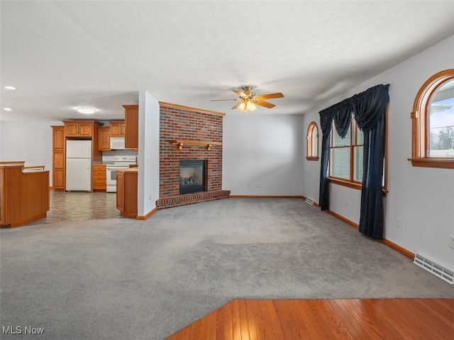 unfurnished living room with ceiling fan, carpet, and a fireplace