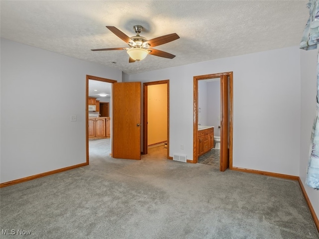 unfurnished bedroom featuring ensuite bathroom, light colored carpet, ceiling fan, and a textured ceiling