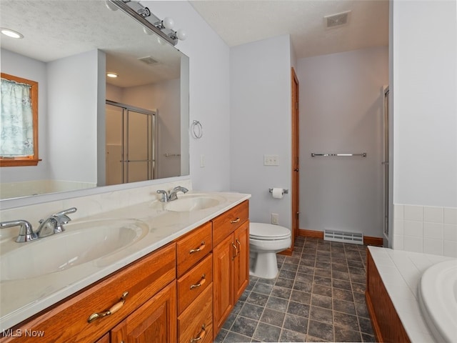 full bathroom with a textured ceiling, toilet, vanity, and separate shower and tub