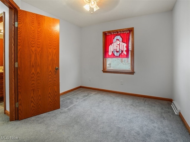 spare room with ceiling fan, a baseboard heating unit, and carpet flooring