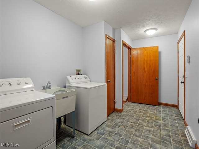 laundry room featuring a textured ceiling, washing machine and clothes dryer, and sink