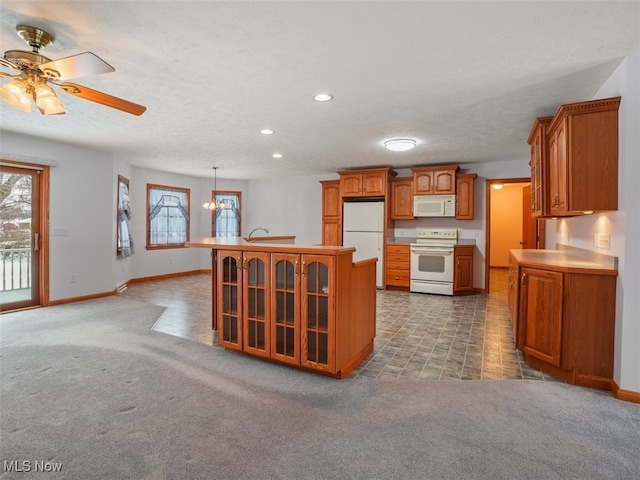 kitchen with carpet floors, white appliances, pendant lighting, ceiling fan with notable chandelier, and a center island