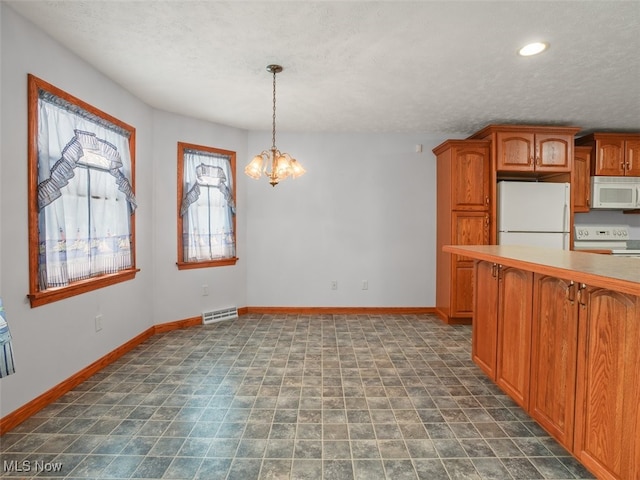 kitchen with a textured ceiling, a chandelier, hanging light fixtures, and white appliances