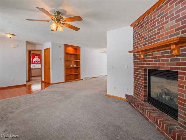 unfurnished living room with light carpet, ceiling fan, a fireplace, and a textured ceiling