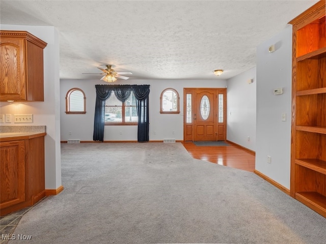 carpeted foyer entrance with a textured ceiling and ceiling fan