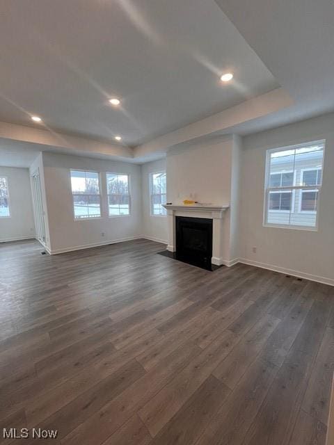 unfurnished living room with dark hardwood / wood-style flooring and a tray ceiling