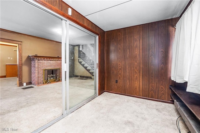 living room featuring light carpet, wooden walls, and a brick fireplace