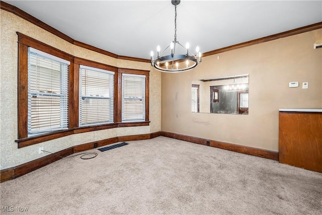 carpeted spare room with plenty of natural light, crown molding, and a notable chandelier